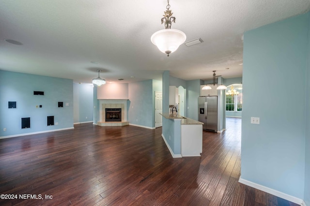 unfurnished living room featuring a fireplace, dark wood-type flooring, sink, and a textured ceiling