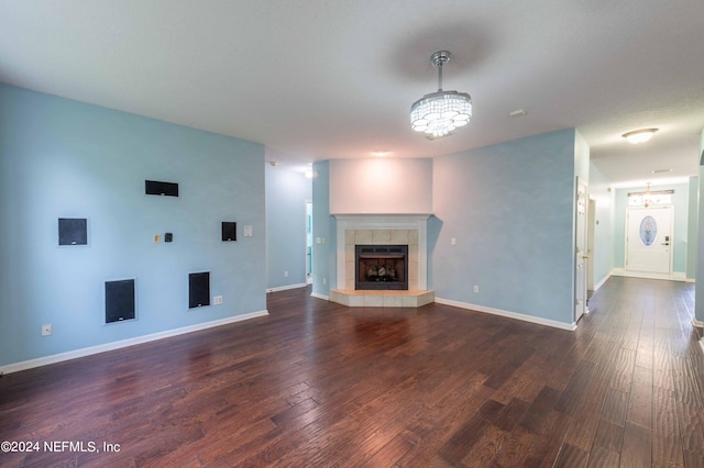 unfurnished living room featuring a fireplace, an inviting chandelier, and dark hardwood / wood-style flooring