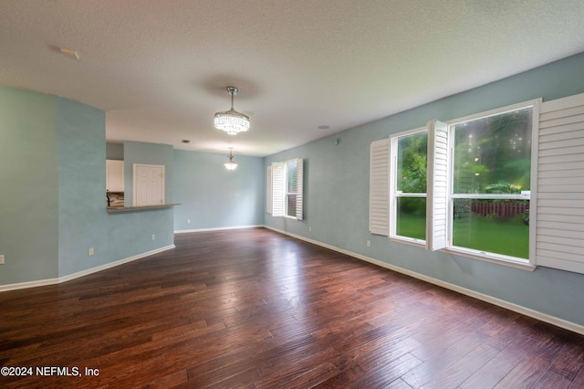 unfurnished room with dark wood-type flooring, a notable chandelier, and a textured ceiling