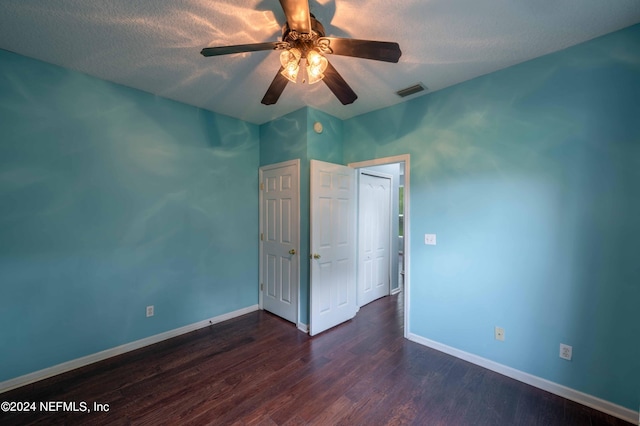 empty room featuring ceiling fan, dark wood-type flooring, and a textured ceiling