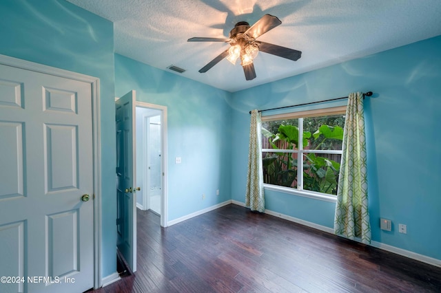 empty room with ceiling fan, a textured ceiling, and dark hardwood / wood-style flooring