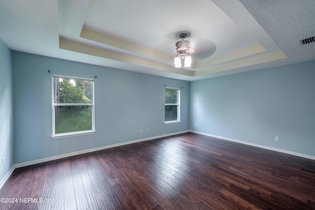 spare room featuring ceiling fan, a textured ceiling, a raised ceiling, and dark wood-type flooring