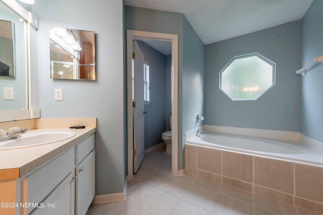 bathroom featuring tile patterned flooring, a relaxing tiled tub, vanity, and toilet