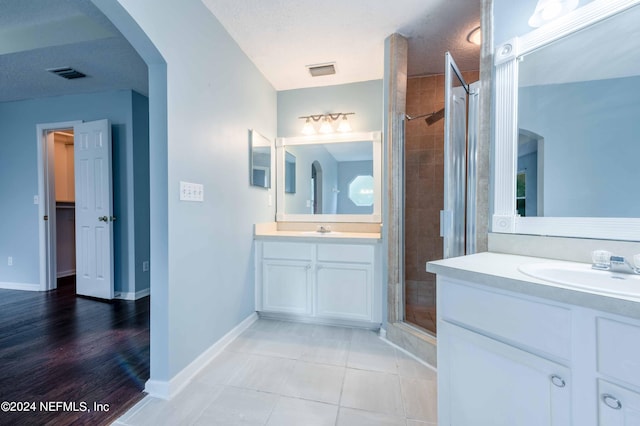 bathroom featuring hardwood / wood-style floors, vanity, an enclosed shower, and a textured ceiling