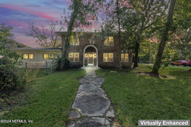 view of front of property with fence, a front lawn, and brick siding