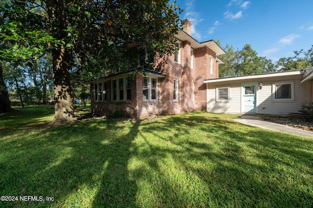 exterior space with brick siding, a lawn, and a chimney