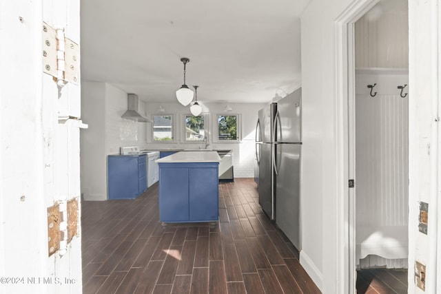 kitchen with blue cabinetry, light countertops, wood tiled floor, a kitchen island, and wall chimney range hood