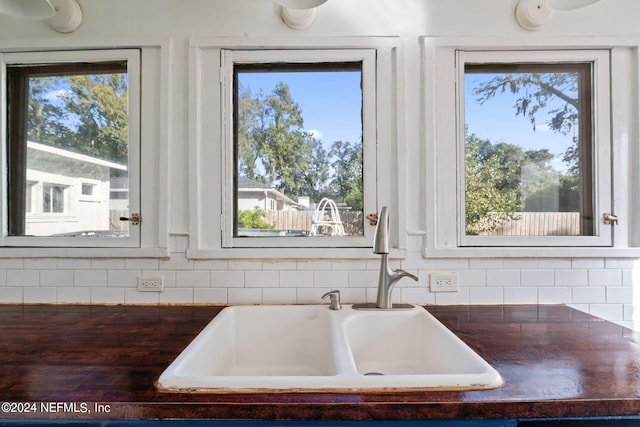 kitchen featuring tasteful backsplash, dark countertops, and a sink