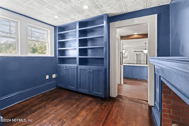 interior space with an ornate ceiling, dark wood finished floors, a fireplace, and baseboards