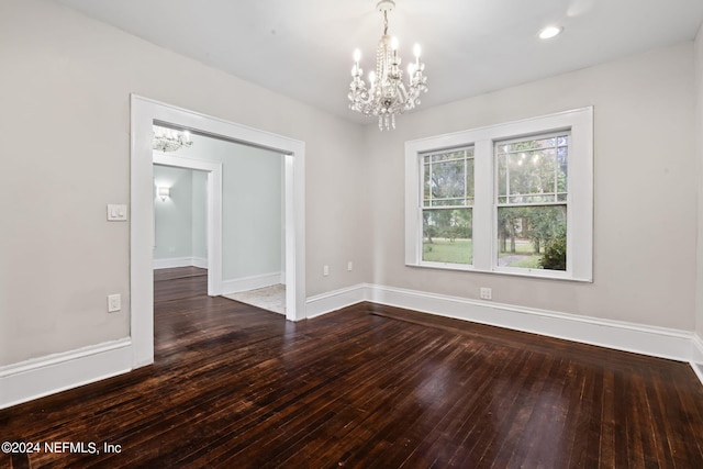 spare room featuring an inviting chandelier, baseboards, hardwood / wood-style floors, and recessed lighting