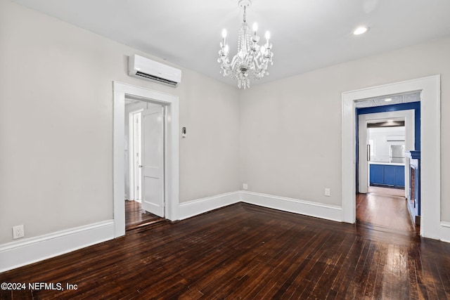 spare room featuring an AC wall unit, hardwood / wood-style flooring, and baseboards