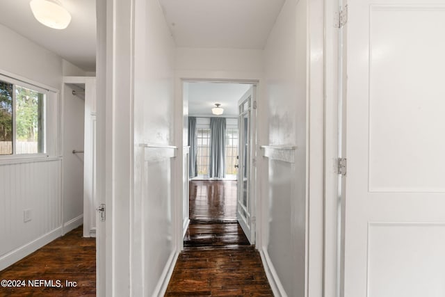 corridor featuring dark wood-style flooring and baseboards