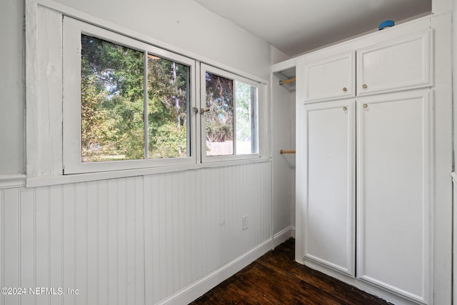 unfurnished bedroom featuring baseboards, dark wood finished floors, and a closet