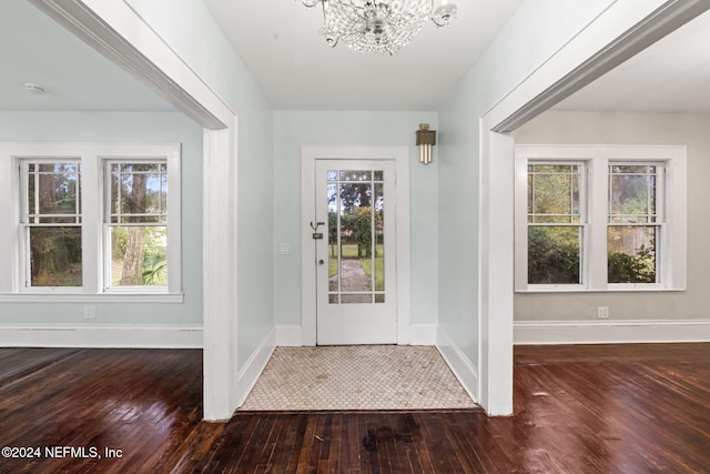 foyer entrance featuring a chandelier, baseboards, a healthy amount of sunlight, and hardwood / wood-style floors