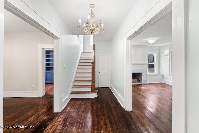 stairs with a fireplace, baseboards, a notable chandelier, and hardwood / wood-style floors