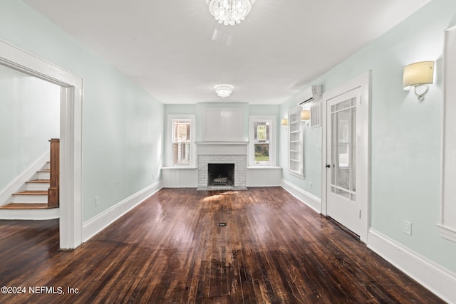 unfurnished living room featuring hardwood / wood-style flooring, a fireplace, baseboards, stairs, and a wall mounted AC