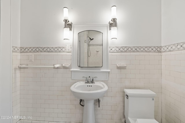 bathroom featuring a shower, wainscoting, tile walls, and toilet