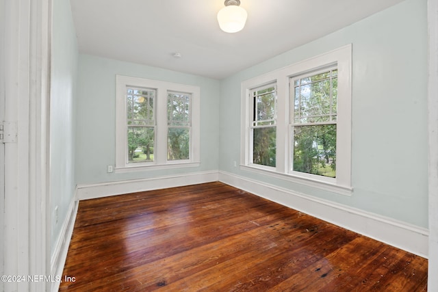 spare room featuring dark wood-style flooring and baseboards