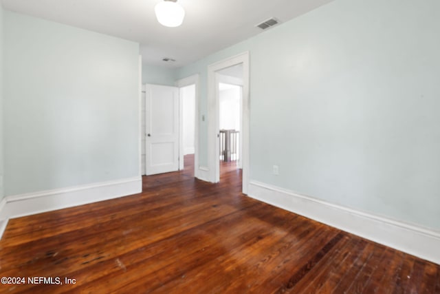 spare room with hardwood / wood-style floors, visible vents, and baseboards