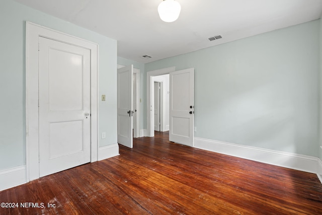 unfurnished room with hardwood / wood-style floors, visible vents, and baseboards