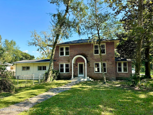 view of front of home with a front lawn, fence, and brick siding