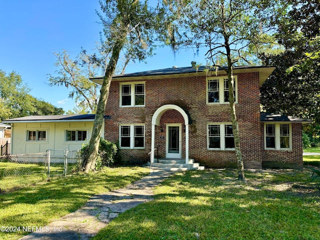 view of front facade with a gate, brick siding, fence, and a front lawn