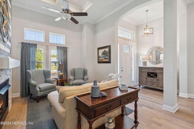 living room featuring ceiling fan with notable chandelier, a high ceiling, light hardwood / wood-style floors, and crown molding