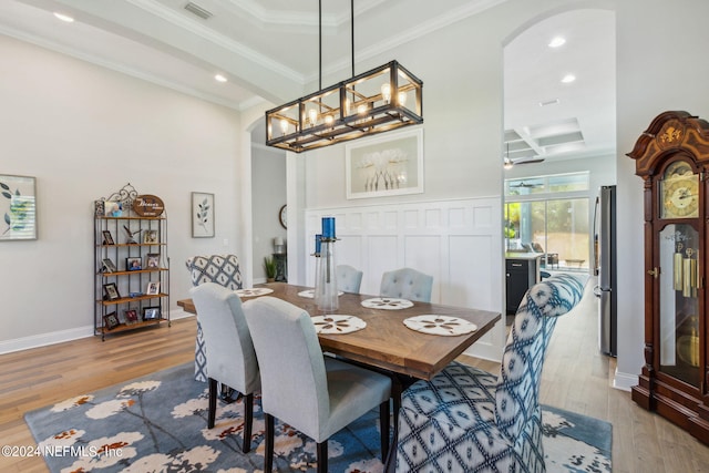 dining room with light hardwood / wood-style flooring, beam ceiling, coffered ceiling, and crown molding