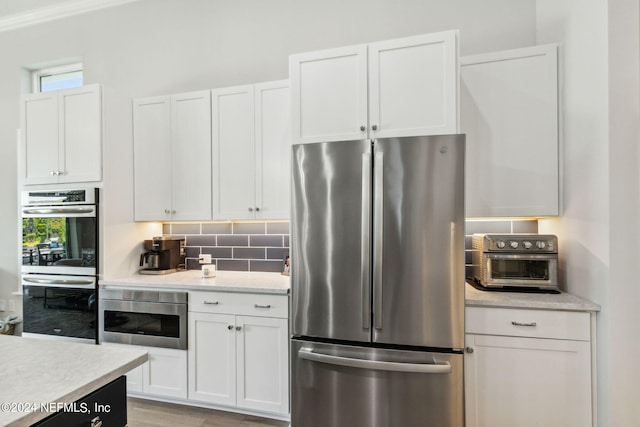 kitchen featuring stainless steel appliances, white cabinetry, and light hardwood / wood-style floors