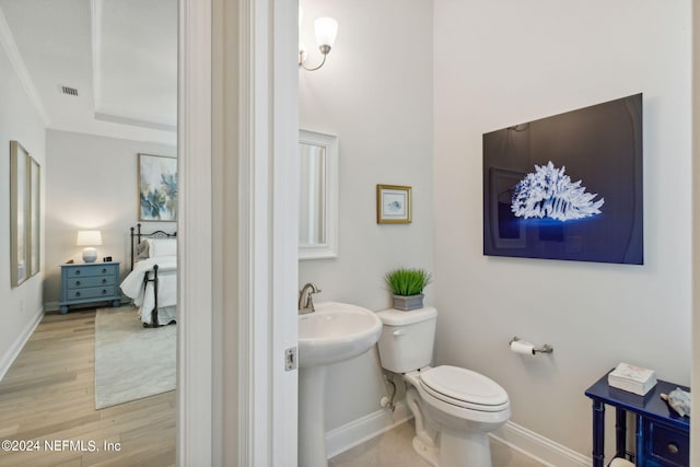 bathroom with wood-type flooring, crown molding, and toilet