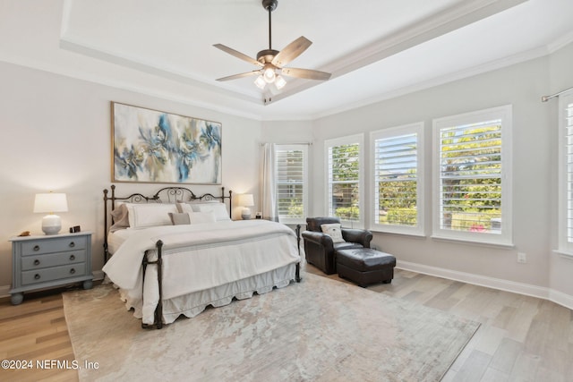 bedroom with a raised ceiling, light hardwood / wood-style floors, crown molding, and ceiling fan