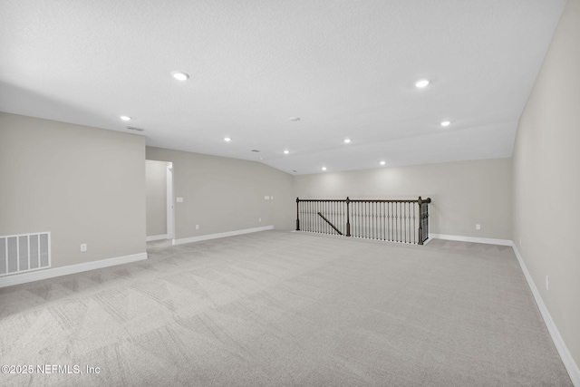 spare room featuring light colored carpet and lofted ceiling