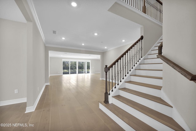 stairs with hardwood / wood-style floors and crown molding