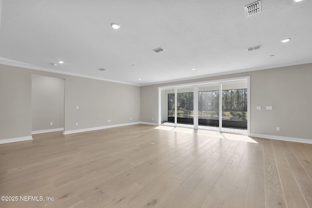 empty room featuring crown molding, light hardwood / wood-style floors, and a textured ceiling