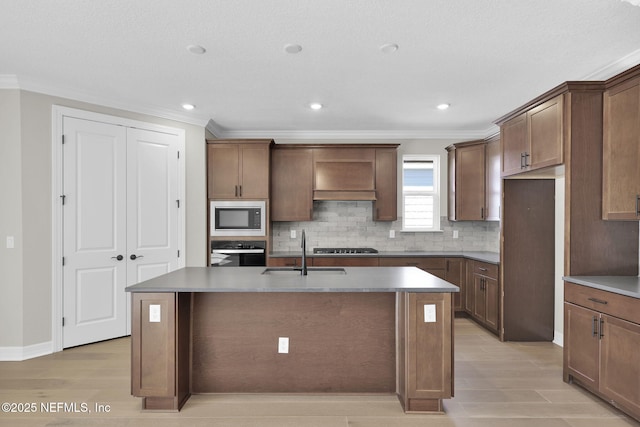 kitchen with sink, a center island with sink, crown molding, and black appliances