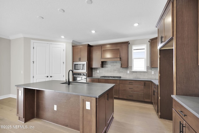 kitchen featuring crown molding, sink, an island with sink, and stainless steel appliances