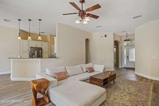 living room featuring dark wood-type flooring, a textured ceiling, and ceiling fan