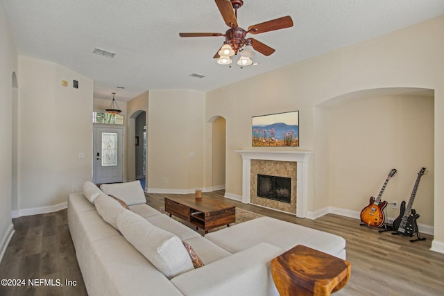 living room featuring hardwood / wood-style floors, a textured ceiling, a fireplace, and ceiling fan