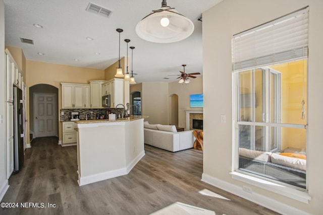 kitchen featuring ceiling fan, appliances with stainless steel finishes, backsplash, dark hardwood / wood-style floors, and pendant lighting