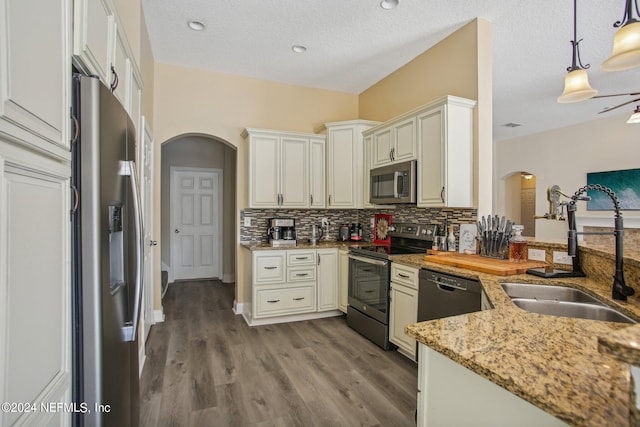 kitchen with hanging light fixtures, sink, light stone countertops, light wood-type flooring, and appliances with stainless steel finishes