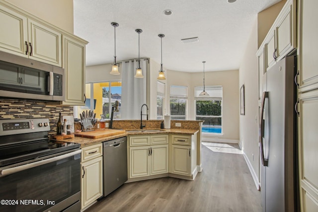 kitchen with stainless steel appliances, sink, pendant lighting, and cream cabinetry