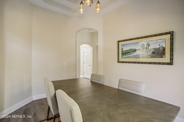 unfurnished dining area with a chandelier, a tray ceiling, and dark hardwood / wood-style flooring