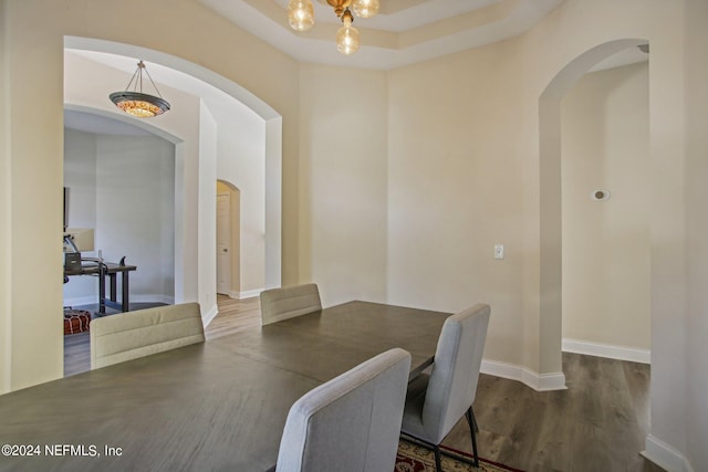 dining space featuring a chandelier, dark hardwood / wood-style floors, and a raised ceiling