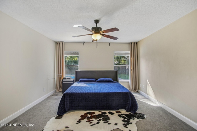 bedroom featuring light carpet, multiple windows, a textured ceiling, and ceiling fan