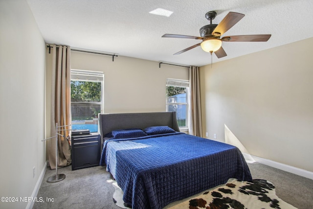 bedroom featuring a textured ceiling, light colored carpet, and ceiling fan