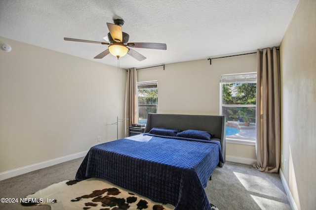 carpeted bedroom with multiple windows, a textured ceiling, and ceiling fan