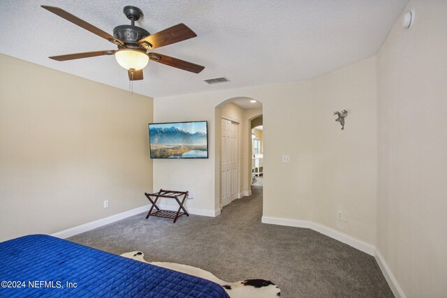 bedroom featuring a closet, a textured ceiling, dark carpet, and ceiling fan