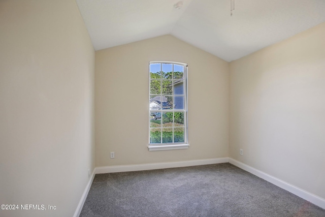 spare room featuring carpet flooring and lofted ceiling