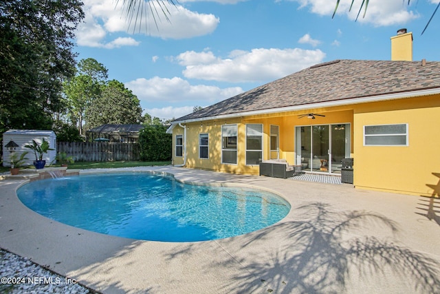 view of pool with a shed, a patio area, pool water feature, and ceiling fan