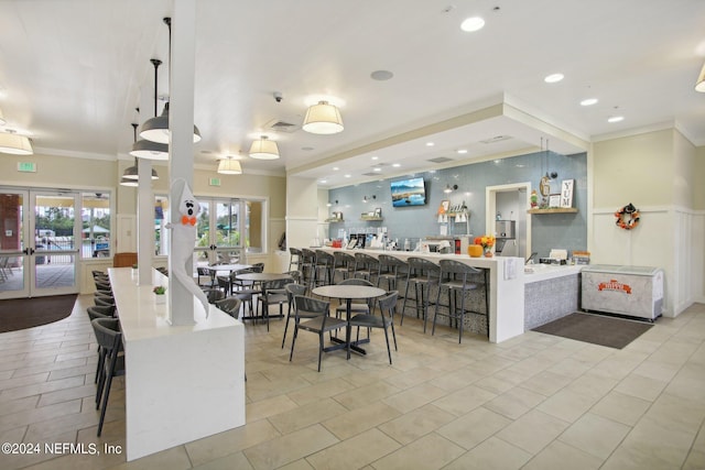 kitchen with french doors, a kitchen breakfast bar, kitchen peninsula, crown molding, and decorative light fixtures